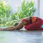 femeie practicand yoga intr-o camera deschisa spre gradina