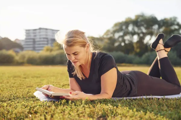 femeie matura sportiva citind o carte in natura