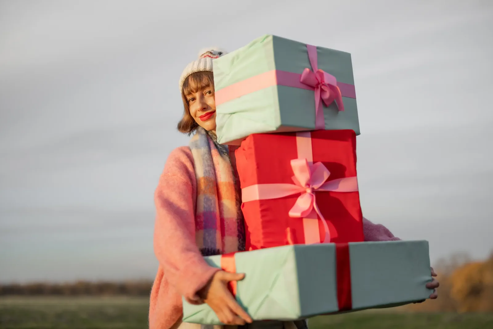 femeie care tine in mana cateva cadouri frumos ambalate