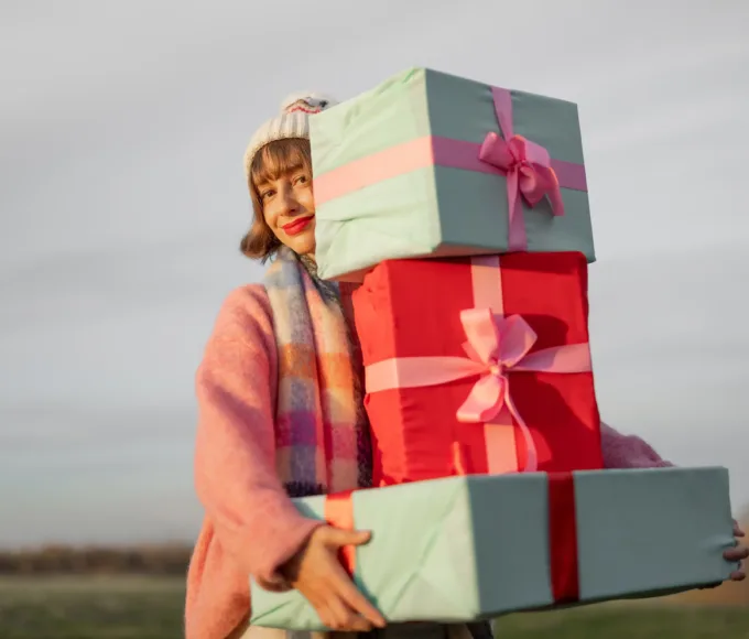 femeie care tine in mana cateva cadouri frumos ambalate