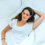 femeie care doarme in pat, cu castile pe cap