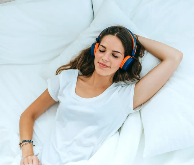 femeie care doarme in pat, cu castile pe cap